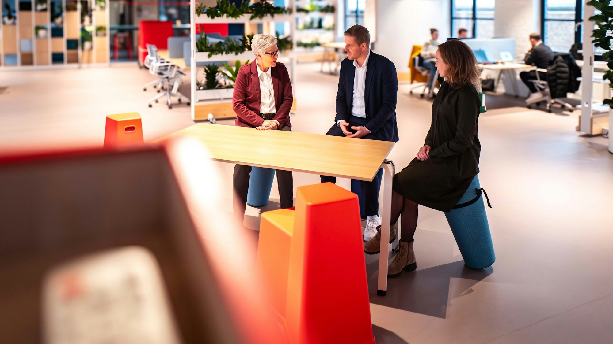 Das Bild zeigt Iris Poth, Wirtschaftsförderin des Kreises Euskirchen, Landrat Markus Ramers und Projektleiterin der Ideenfabrik, Isabelle Jaeschke, an einem Tisch in der Ideenfabrik.