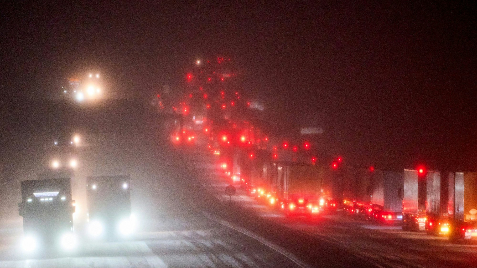 Lastwagen stauen sich nach einem Verkehrsunfall auf der schneebedeckten Autobahn A3 kurz hinter der Anschlussstelle Mogendorf im Westerwaldkreis in Fahrtrichtung Köln.