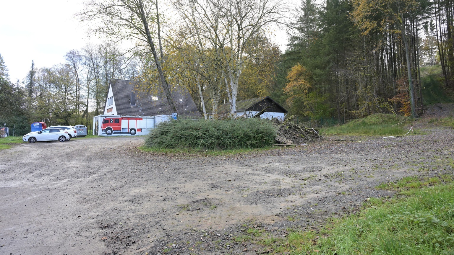 Ein Feuerwehrgerätehaus, daneben ein großer, unbefestigter Parkplatz.