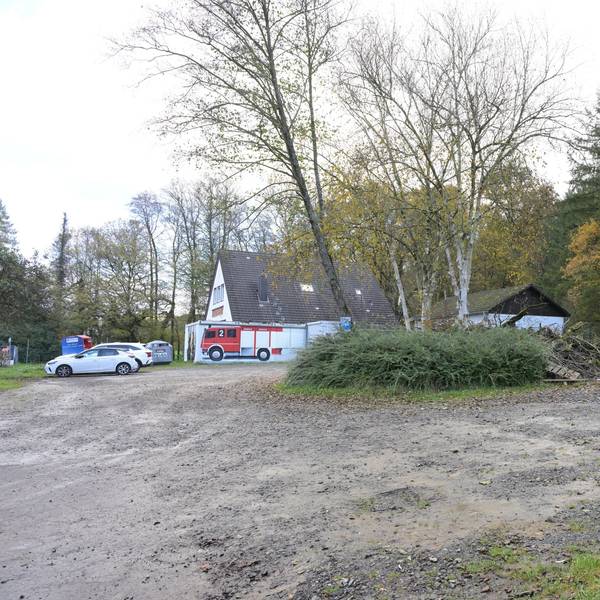 Ein Parkplatz, im Hintergrund ein Feuerwehrgerätehaus.