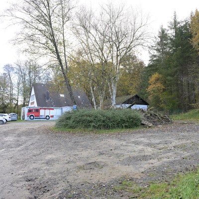 Ein Parkplatz, im Hintergrund ein Feuerwehrgerätehaus.