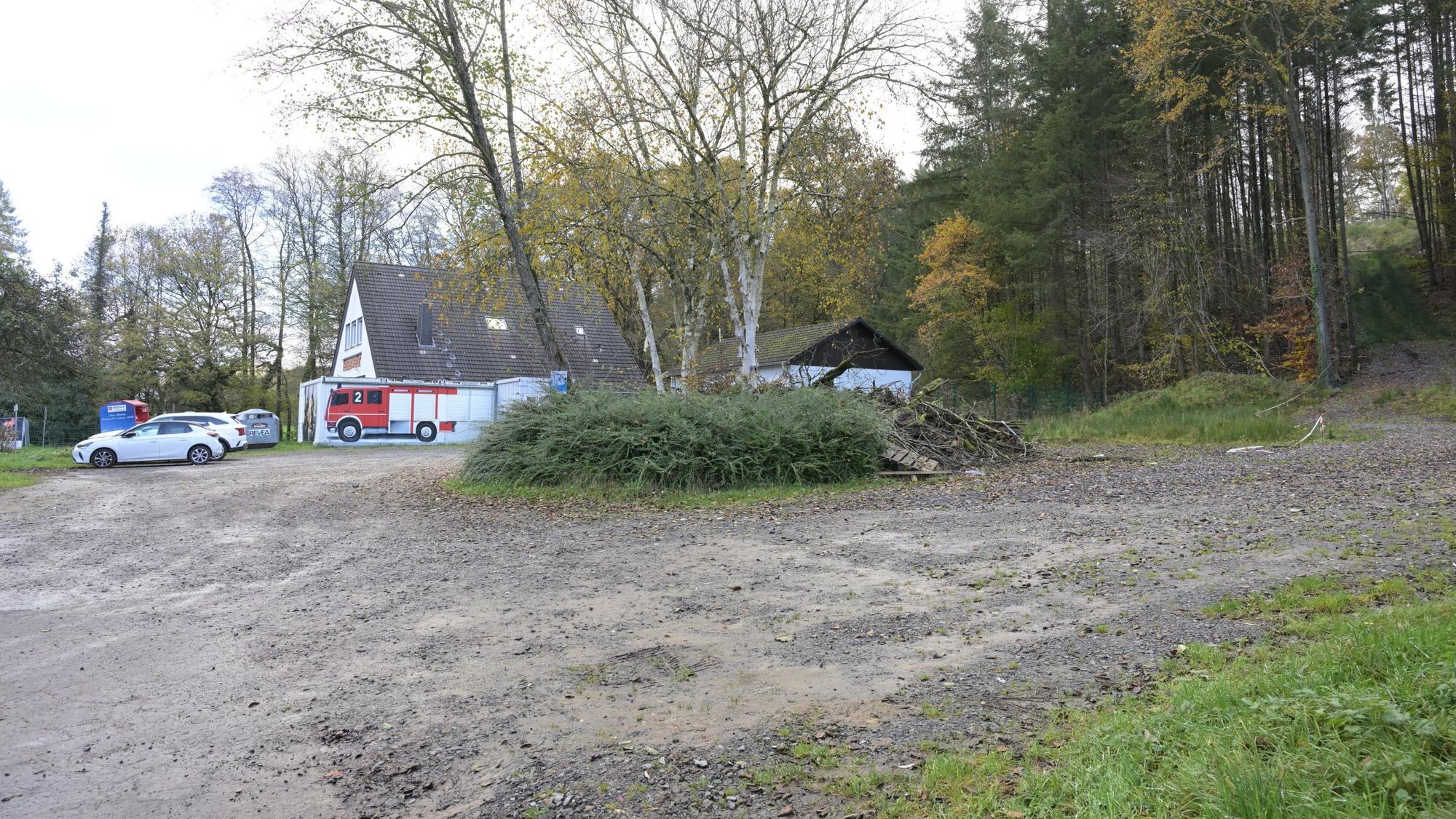 Ein Feuerwehrgerätehaus, daneben ein großer, unbefestigter Parkplatz.