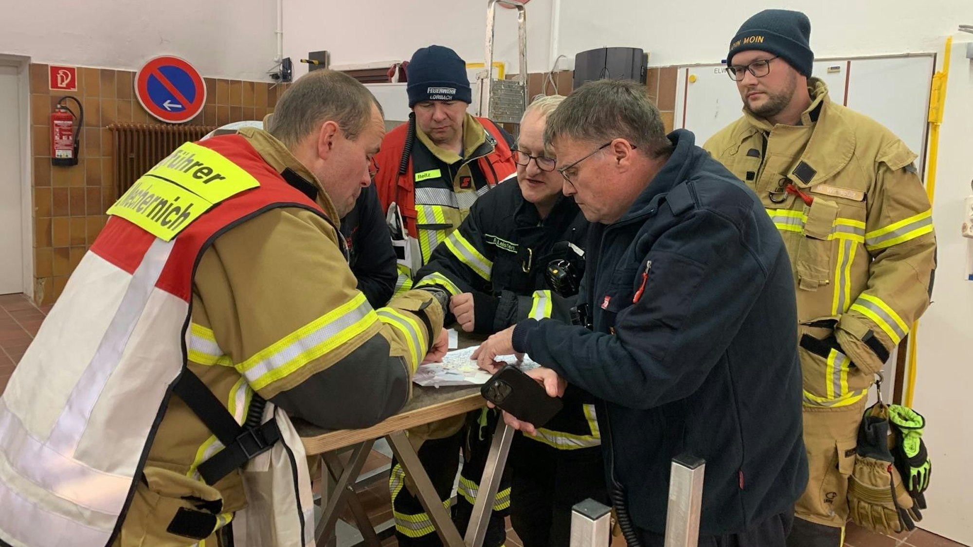 Das Bild zeigt einige Feuerwehrleute während einer Lagebesprechung.