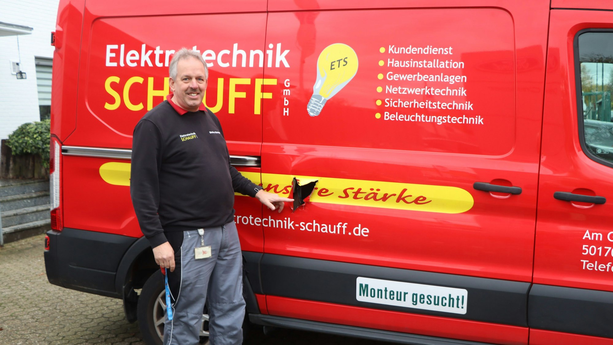 Das Foto zeigt einen Handwerker vor seinem roten Firmenfahrzeug.