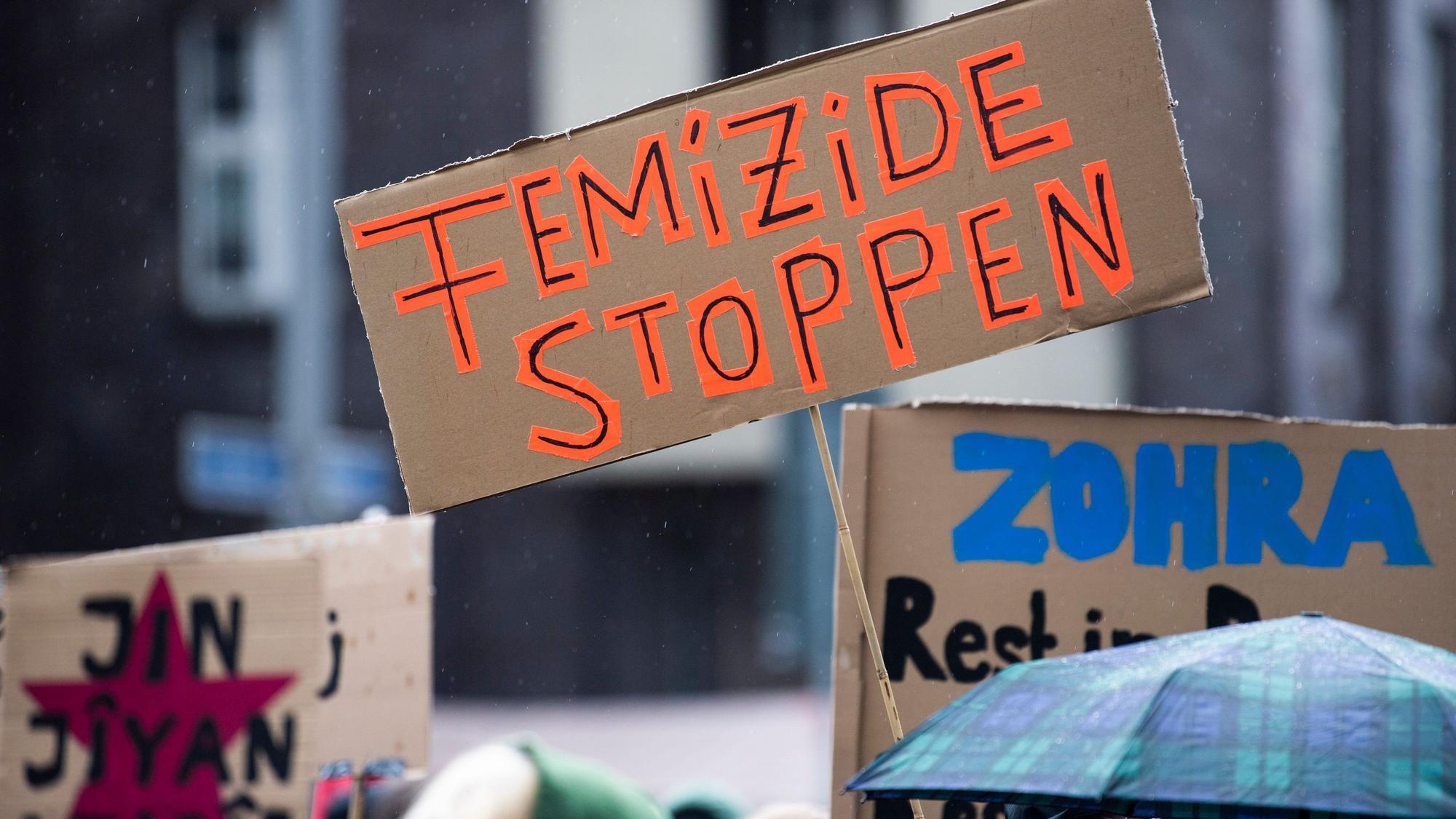 Bei einer Demonstration gegen Gewalt an Frauen hält eine Teilnehmerin ein Plakat mit der Aufschrift „Femizide stoppen“.
