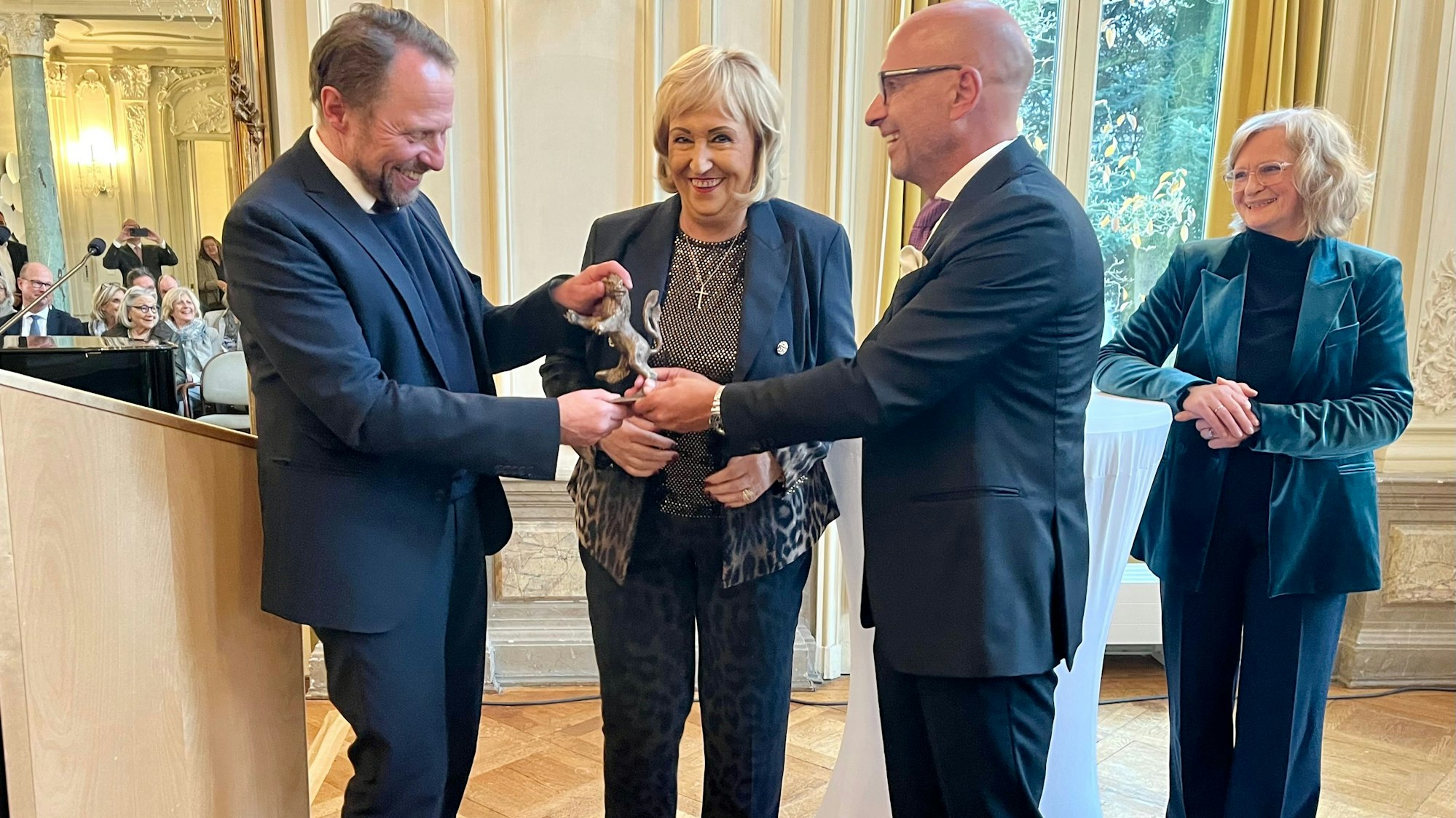 Marianne Müller erhält den Leverkusener Löwen von Uwe Richrath und Uwe Beenen, Laudatorin Johanna Gastdorf schaut zu.