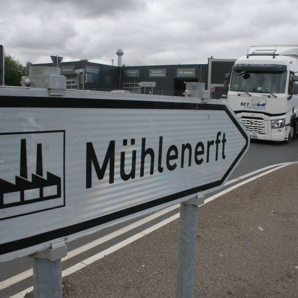 Zu sehen ist ein Straßenschild, das den Weg in das Gewerbegebiet Mühlenerft weist, und ein Lkw.
