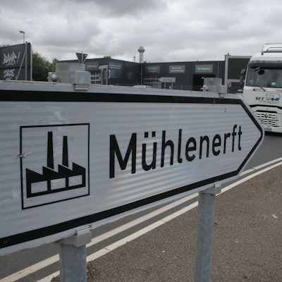 Zu sehen ist ein Straßenschild, das den Weg in das Gewerbegebiet Mühlenerft weist, und ein Lkw.