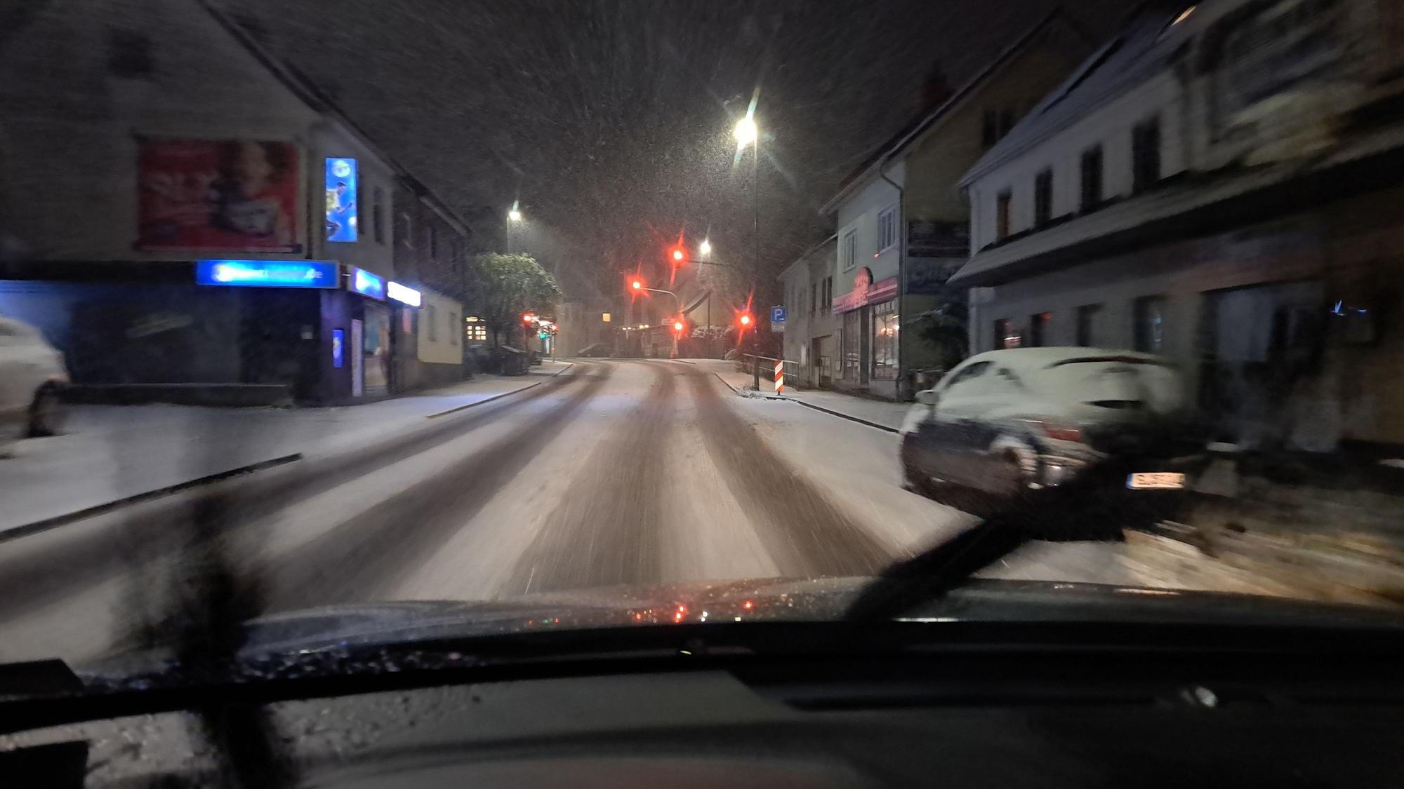 Durch die Windschutzscheibe eines Autos ist die verschneite Bensberger Straße in Bergisch Gladbach-Heidkamp zu sehen.