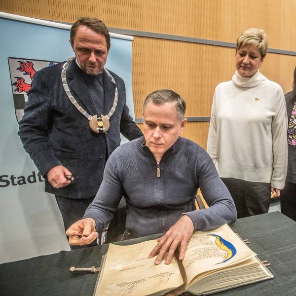 Bürgermeister Oleksandr Saiduk und seine Delegation (rechts) aus Nikopol tragen sich ins Goldene Buch ein. Links Oberbürgermeister Uwe Richrath mit Amtskette.