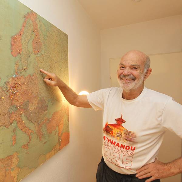 Hanno Rheineck steht vor einer Landkarte, in der seine Reiseziele markiert sind.