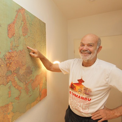 Hanno Rheineck steht vor einer Landkarte, in der seine Reiseziele markiert sind.