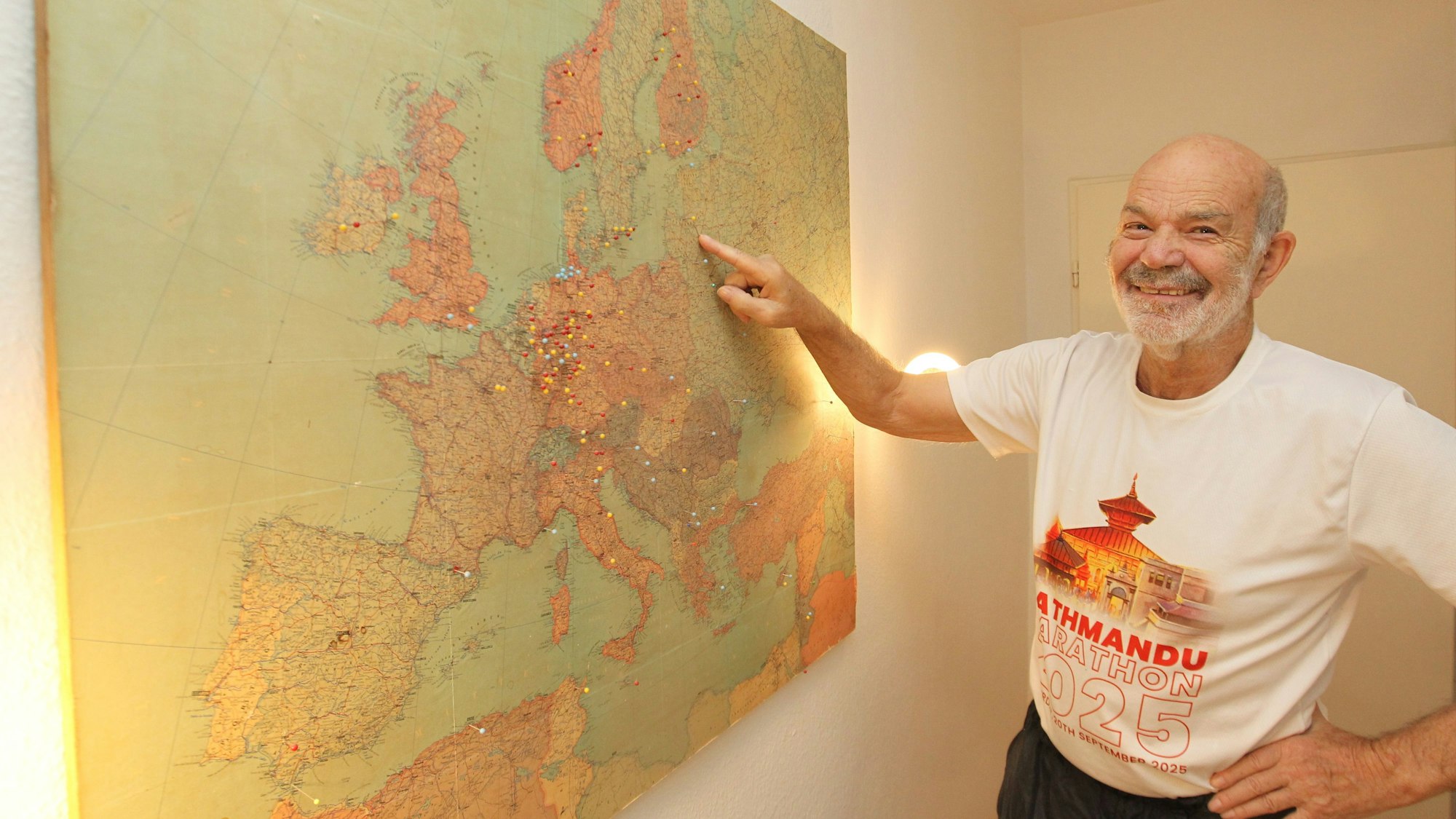 Hanno Rheineck steht vor einer Landkarte, in der seine Reiseziele markiert sind.