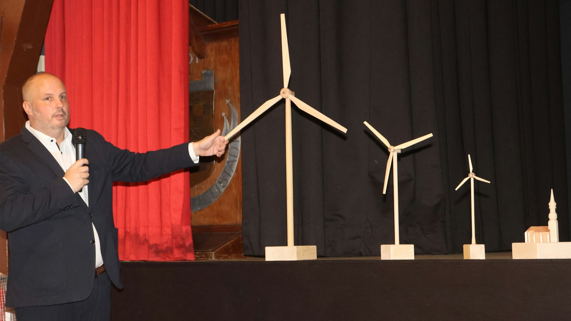 Bergneustadts Bürgermeister Matthias Thul demonstriert das Größenverhältnis der neuen Windräder im Vergleich zu bestehenden Gebäuden