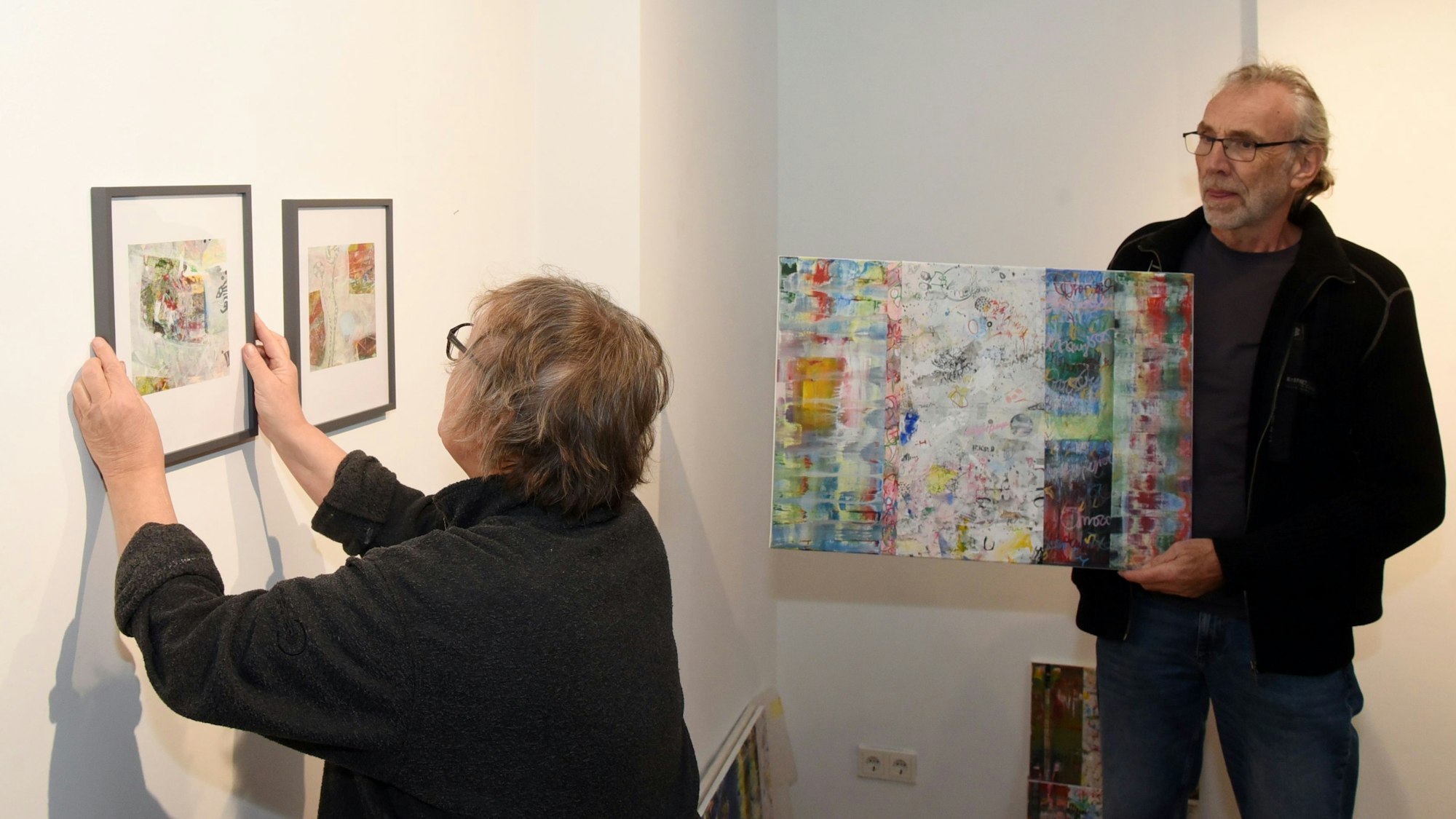 Eine Frau hängt Bilder auf.