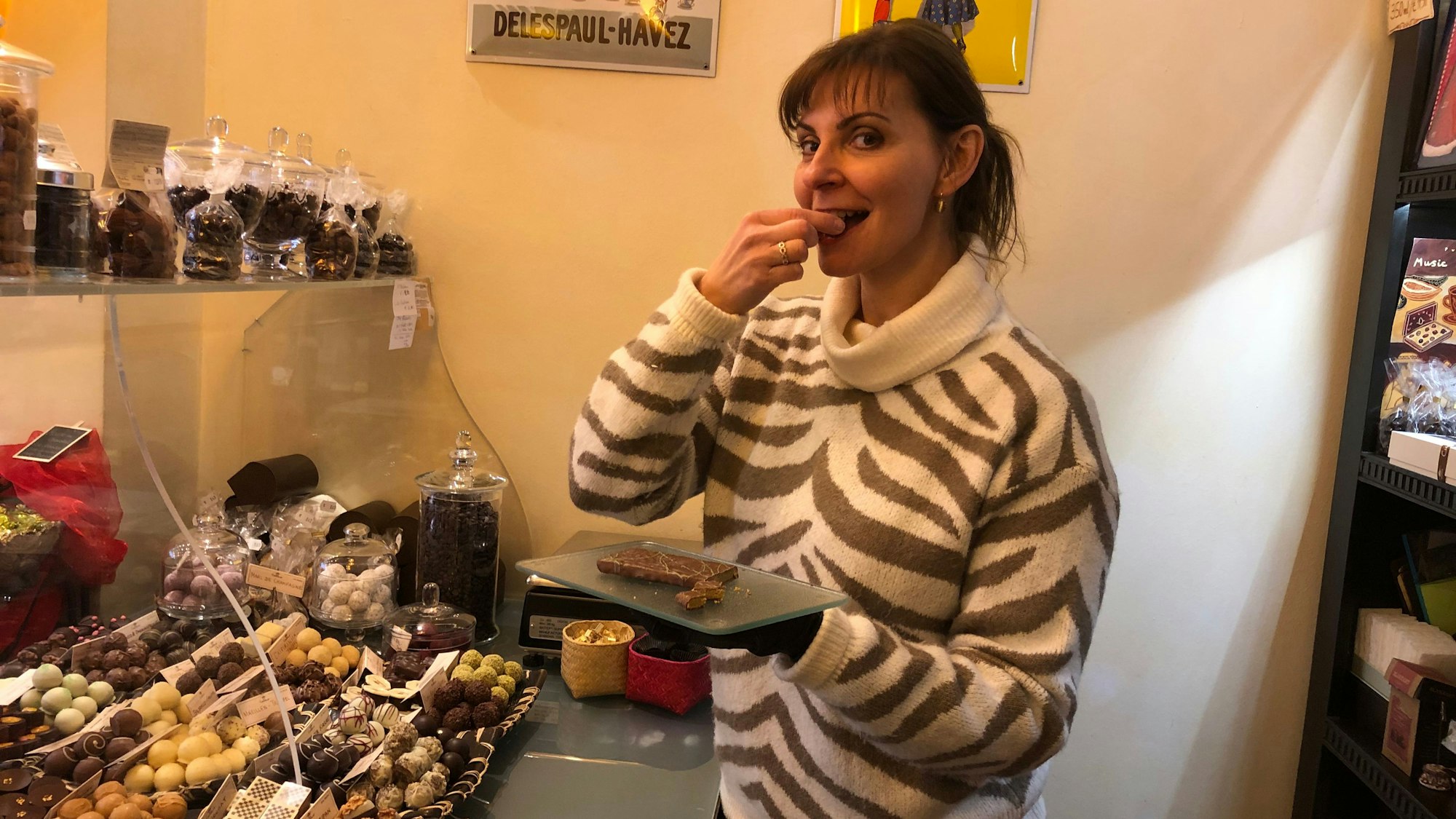 Eine Frau in einem Süßwarengeschäft beißt in ein Stück Schokolade.