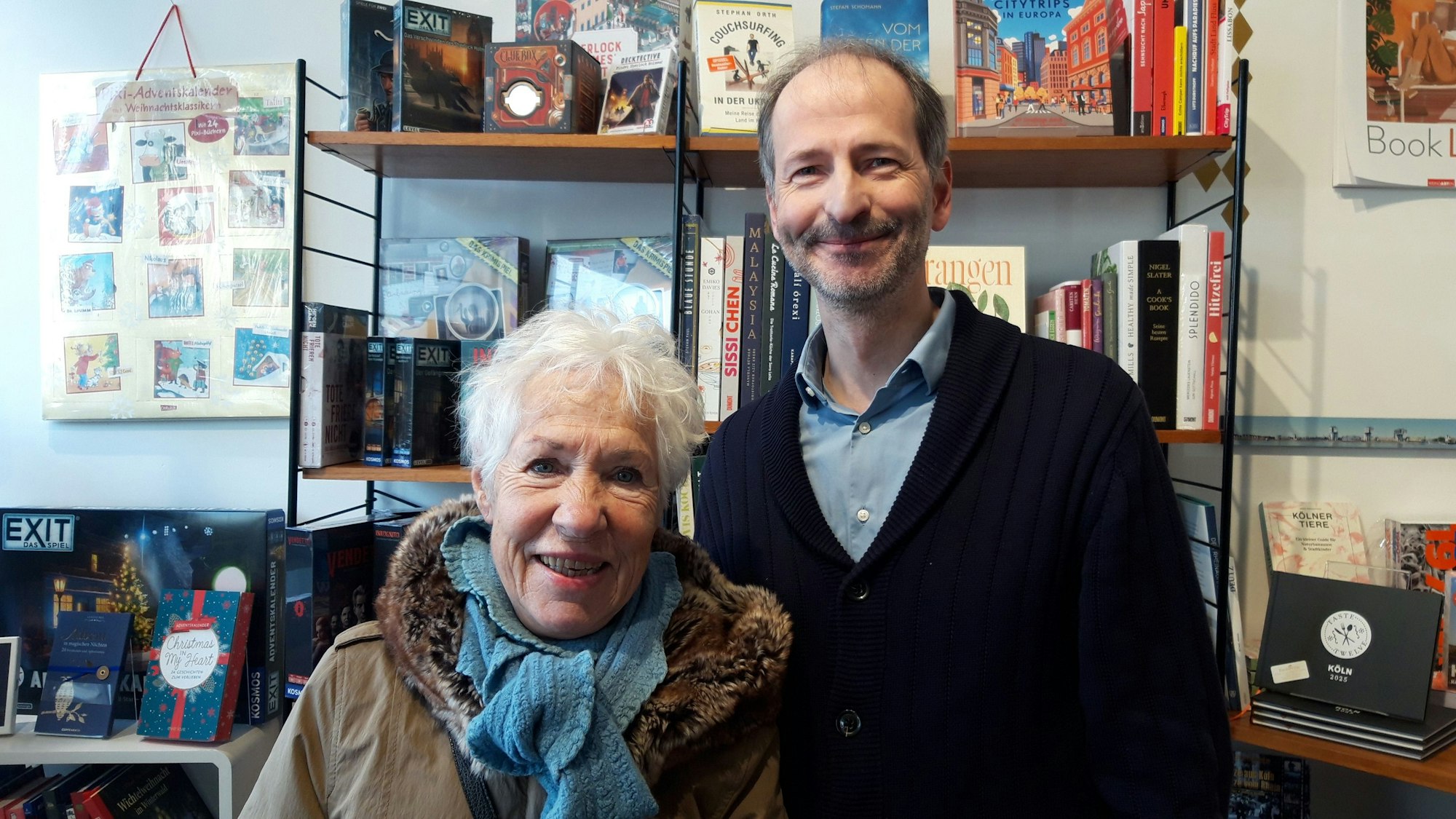 Ein Mann und eine Frau stehen vor einem Bücherregal in einer Buchhandlung.