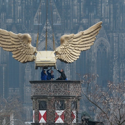 Das Flügelauto des Aktionskünstlers HA Schult hängt an einem Kran und wird auf den Turm des Kölnischen Stadtmuseums in Köln gesetzt.