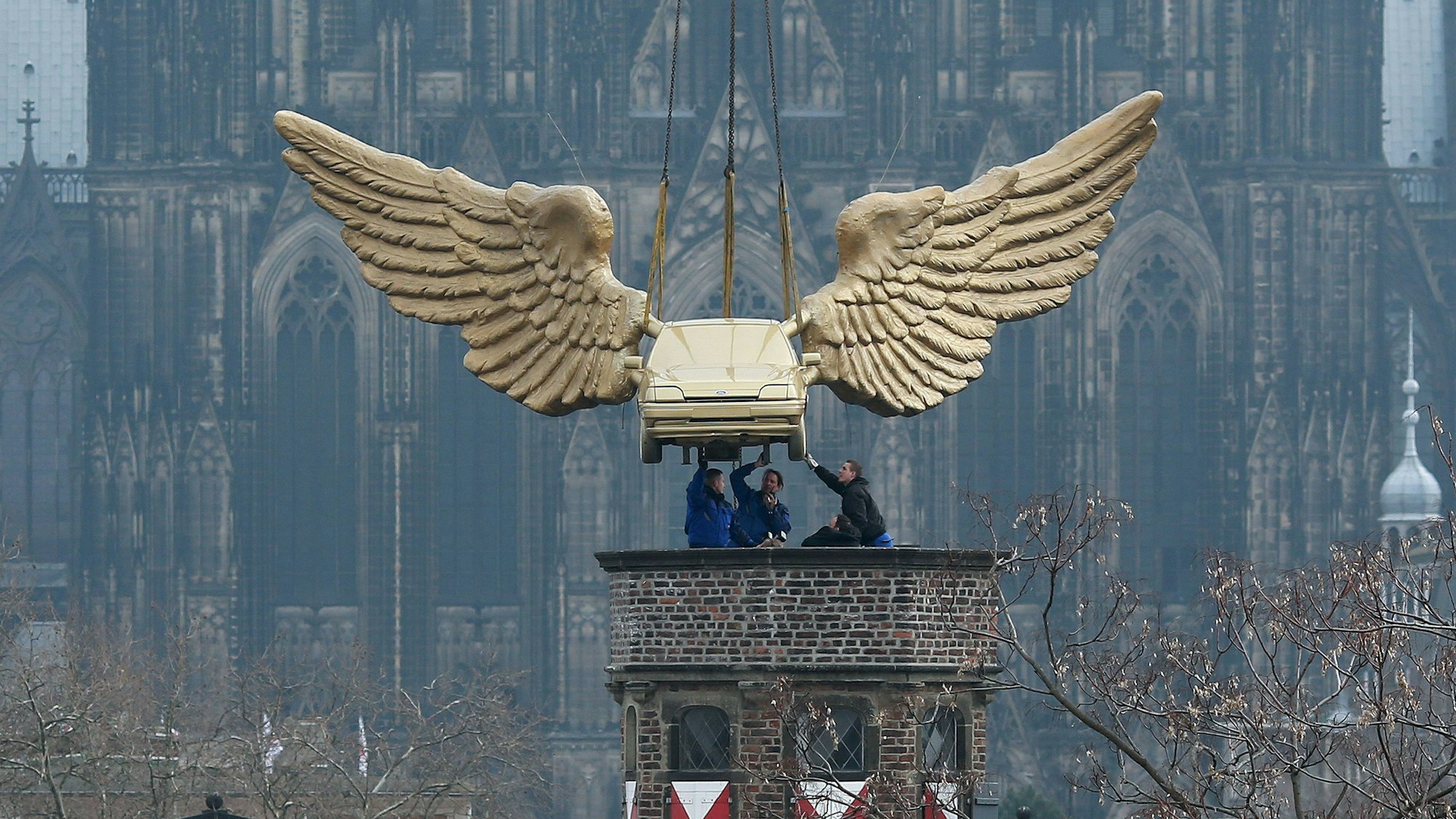 Das Flügelauto des Aktionskünstlers HA Schult hängt an einem Kran und wird2013 nach einer Restaurierung auf den Turm des Kölnischen Stadtmuseums in Köln gesetzt.