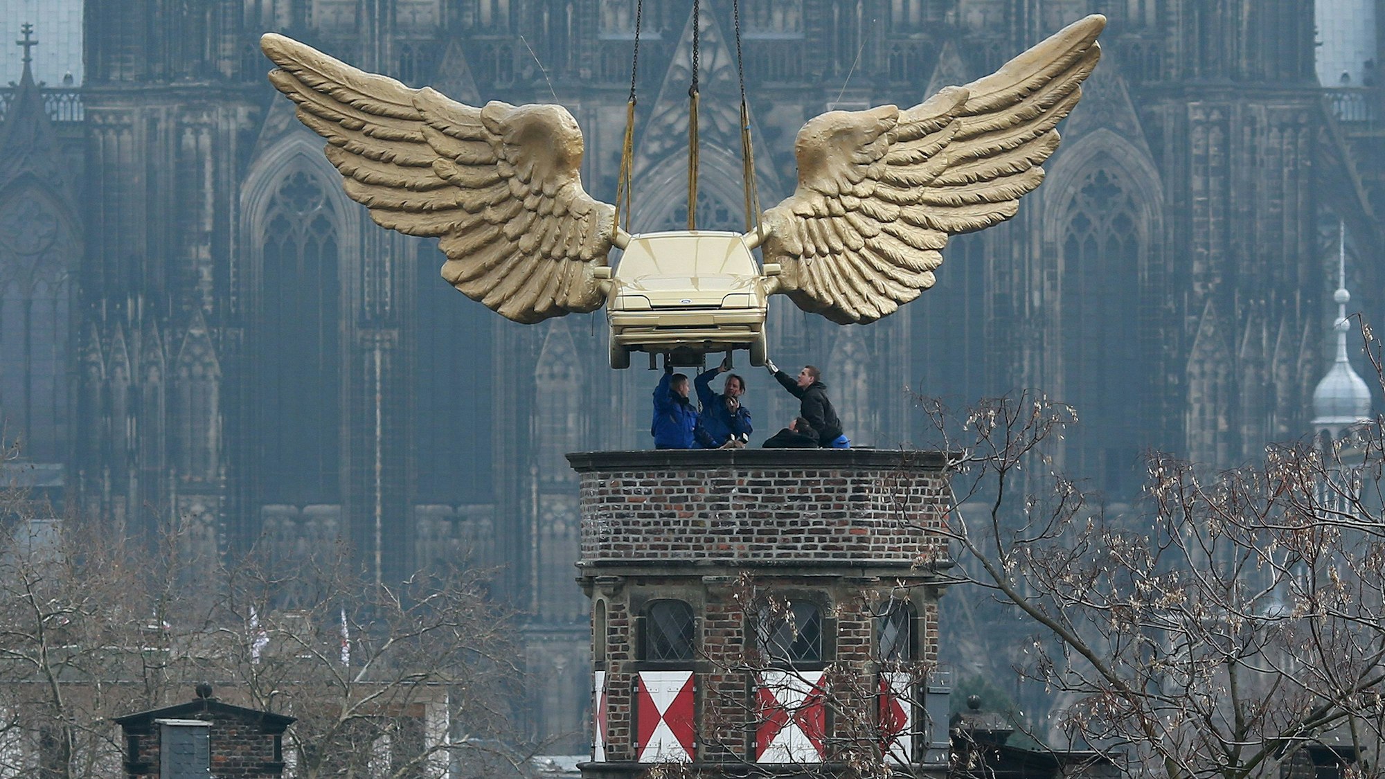 Das Flügelauto des Aktionskünstlers HA Schult hängt an einem Kran und wird auf den Turm des Kölnischen Stadtmuseums in Köln gesetzt.