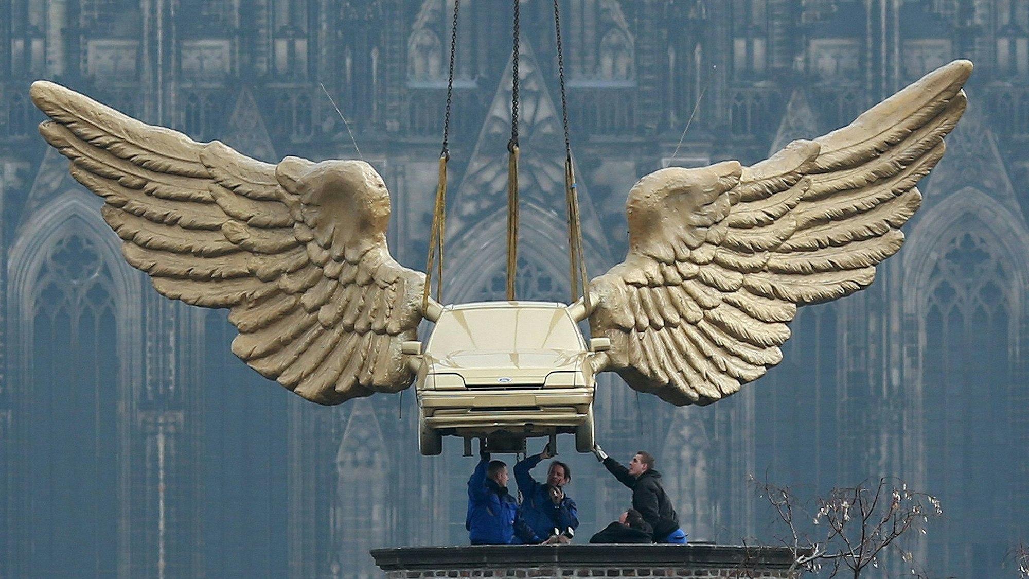 Das Flügelauto des Aktionskünstlers HA Schult hängt an einem Kran und wird auf den Turm des Kölnischen Stadtmuseums in Köln gesetzt.