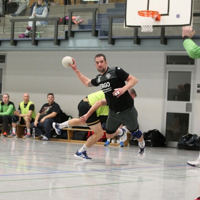 Simon Wilms beim Wurf auf das Tor, im Hintergrund schauen andere Spieler zu.