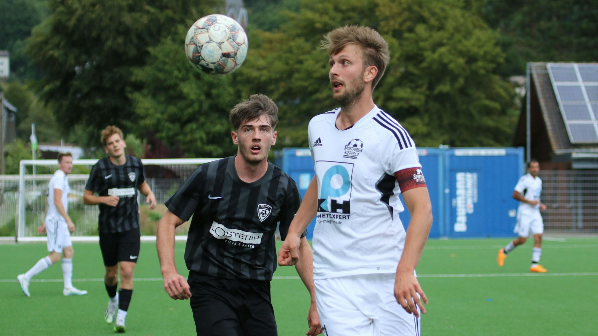 Zwei Fußballer fixieren mit den Augen den herannahenden Ball.
