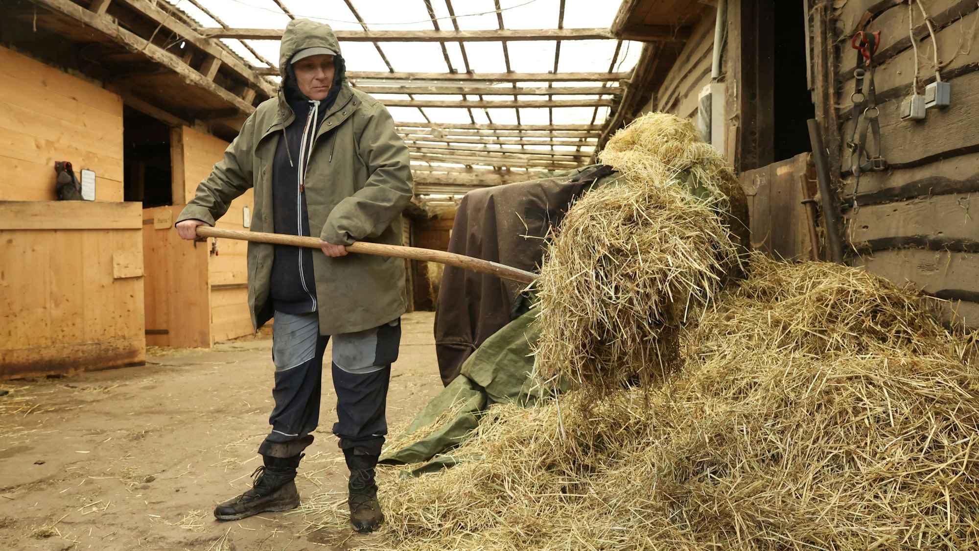 Bettina Jung hält eine Mistgabel voller Stroh.