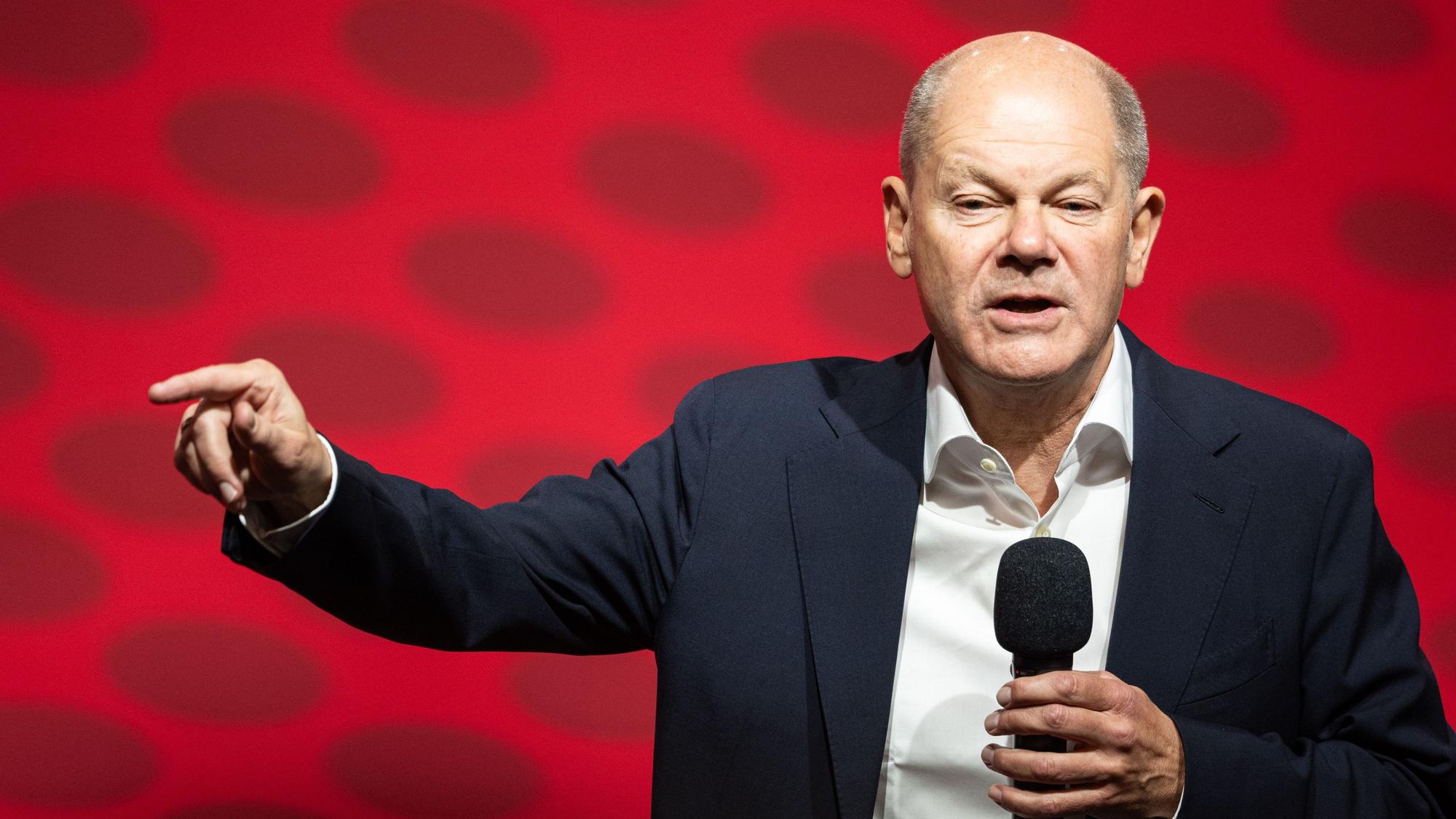 Olaf Scholz bei einer Rede, mit Mikrofon in der Hand.