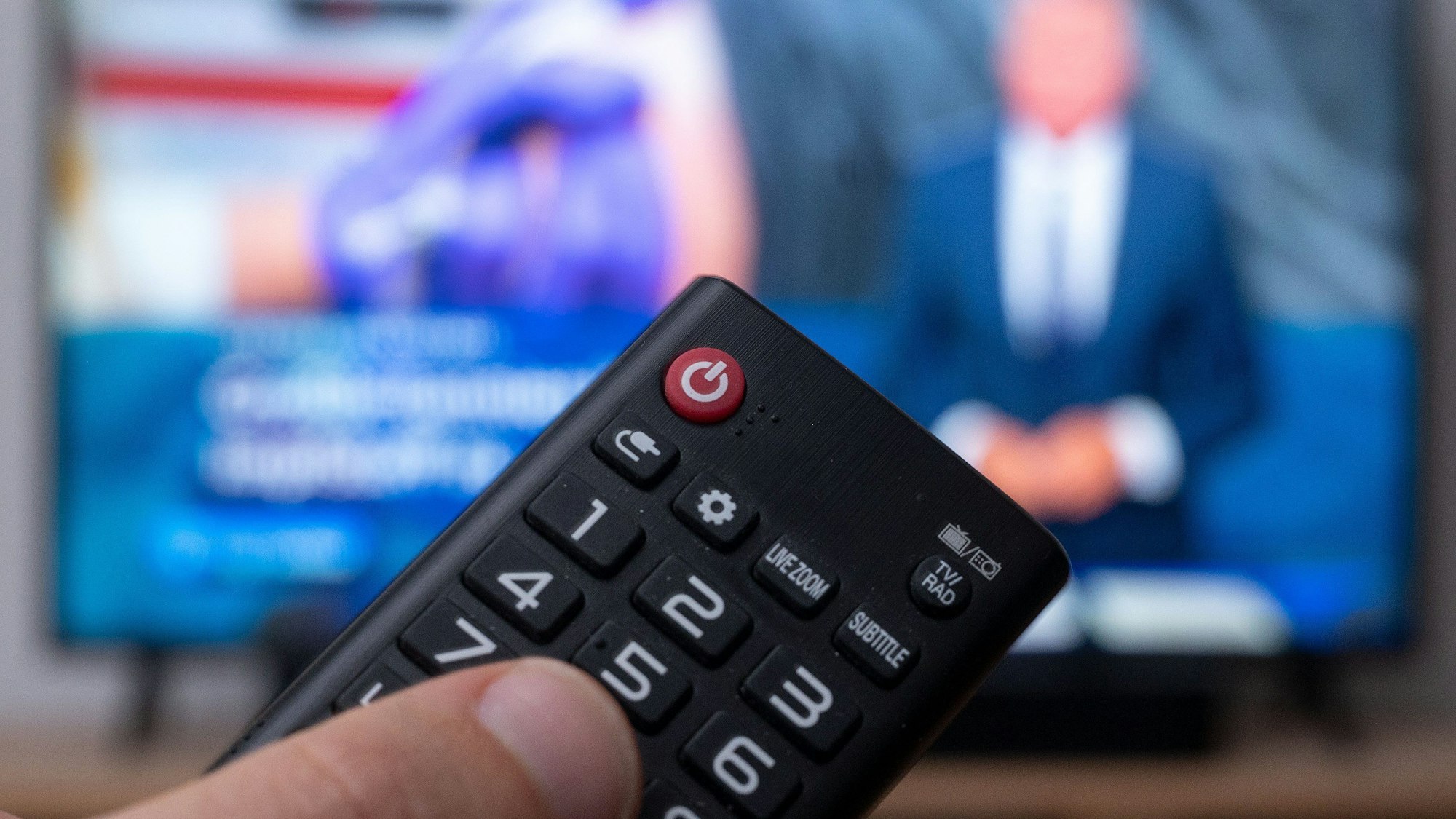 Ein Mann mit Fernbedienung vor einem Fernseher