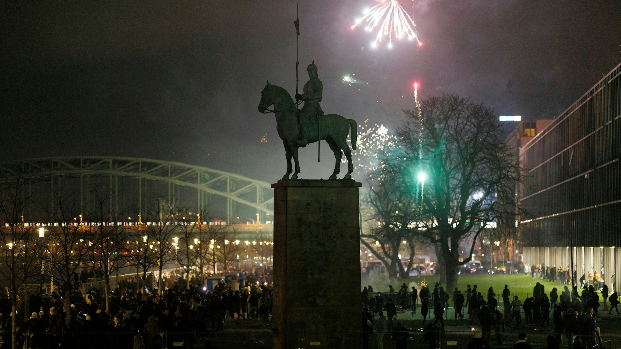 Das Foto zeigt eine Menschenmenge und Feuerwerk am Rheinufer in Köln.