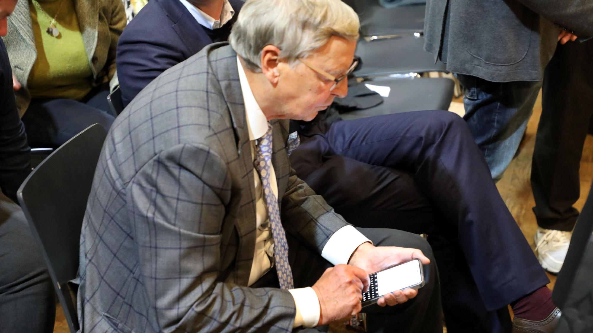 Wolfgang Bosbach schaut auf sein Handy und tippt darauf.