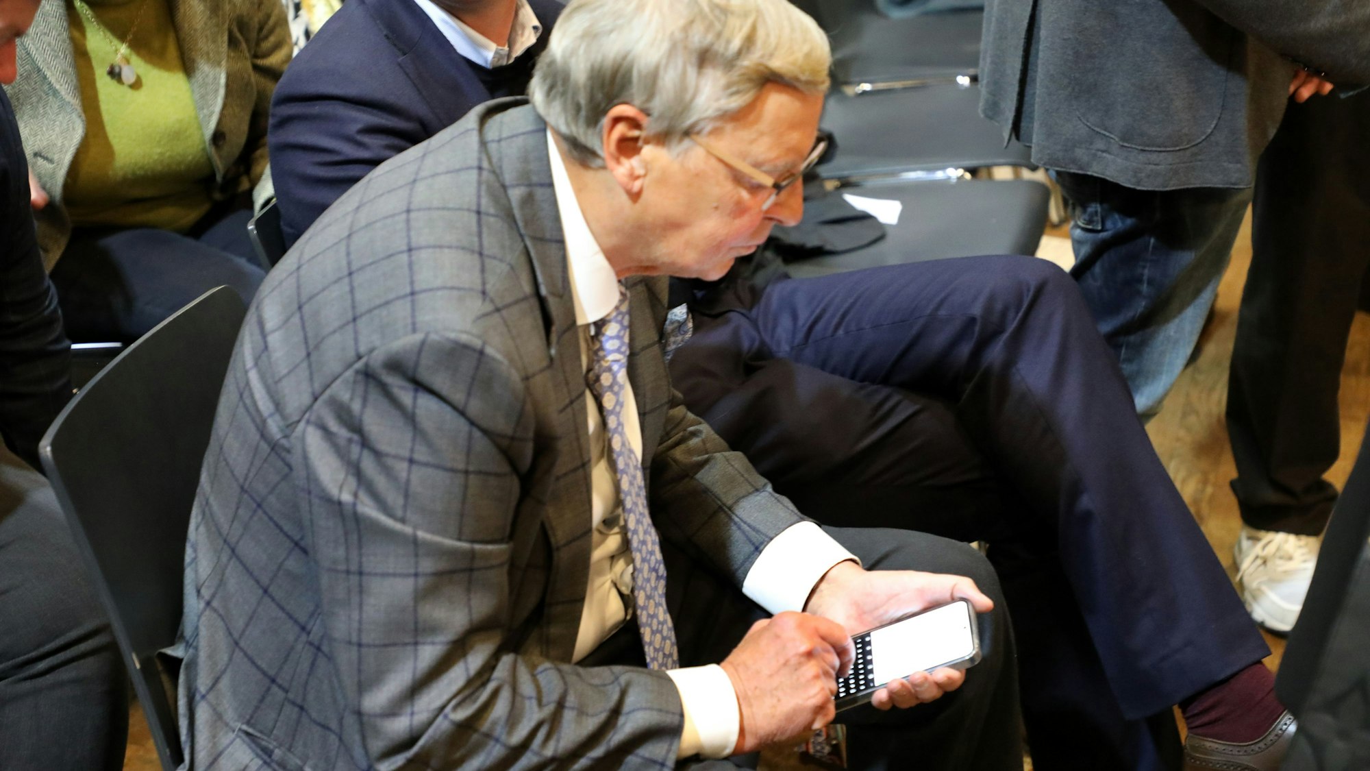 Wolfgang Bosbach schaut auf sein Handy und tippt darauf.