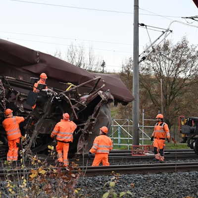 Das Bild zeigt mehrere Arbeiter an einem verunglückten Waggon.