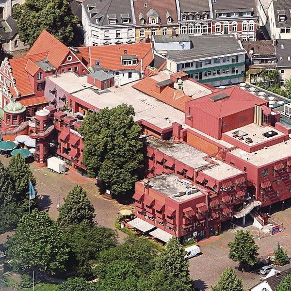 Die Luftaufnahme des Gebäudekomplexes zeigt die roten Metalllackierungen der Fassade.