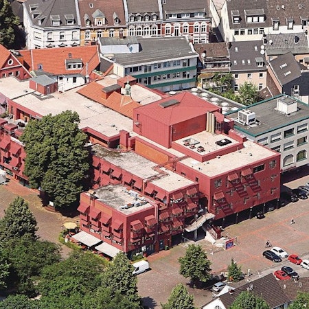 Die Luftaufnahme des Gebäudekomplexes zeigt die roten Metalllackierungen der Fassade.