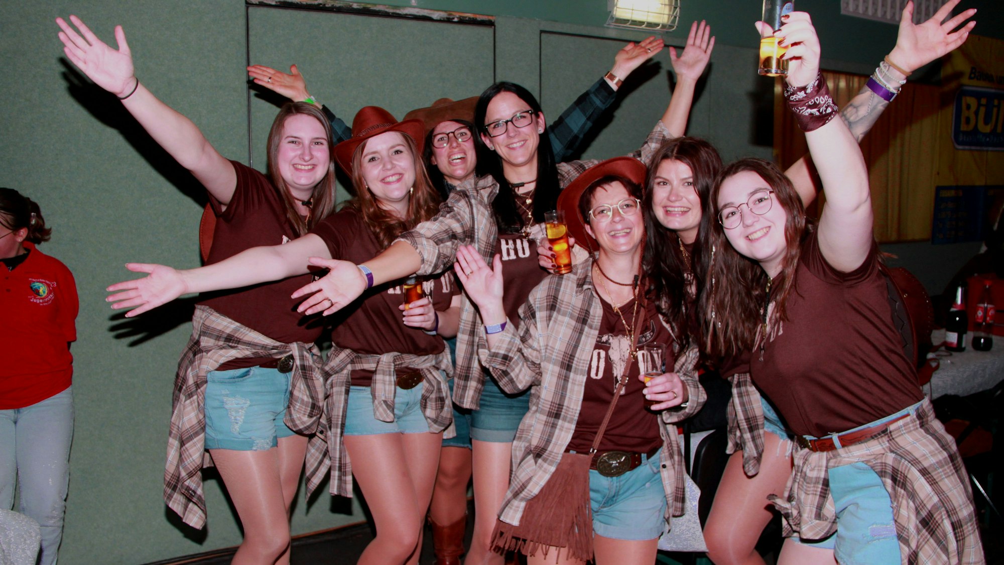 Die Arme ausgebreitet, ein Glas in der Hand lächeln die Erzieherinnen der Kita Nettersheim-Zingsheim in die Kamera.