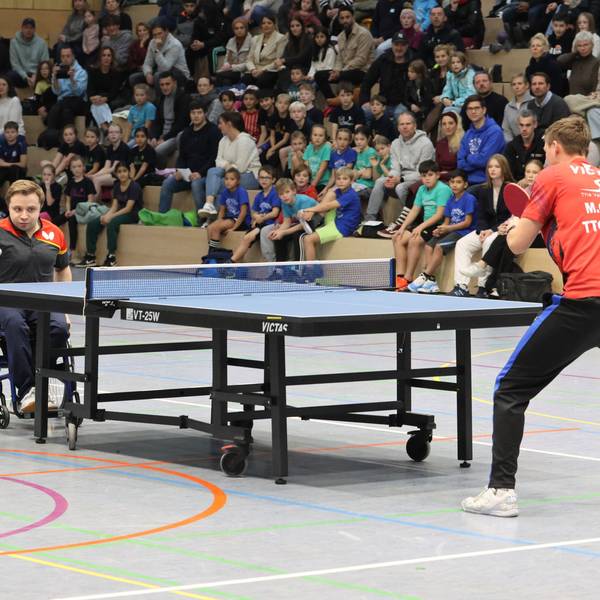 Ein Mann im Rollstuhl spielt gegen einen Stehenden.