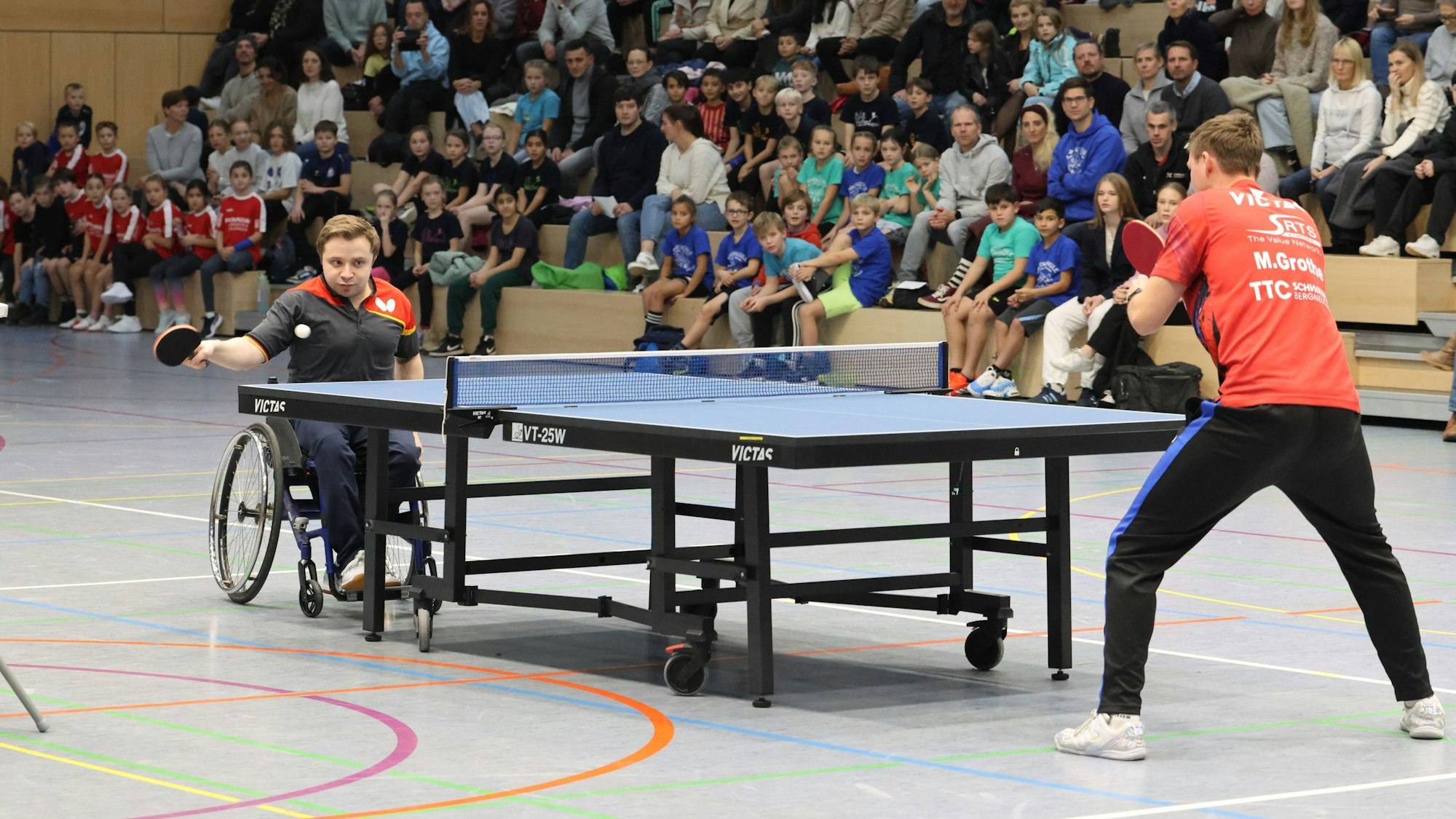 Ein Mann im Rollstuhl spielt gegen einen Stehenden.