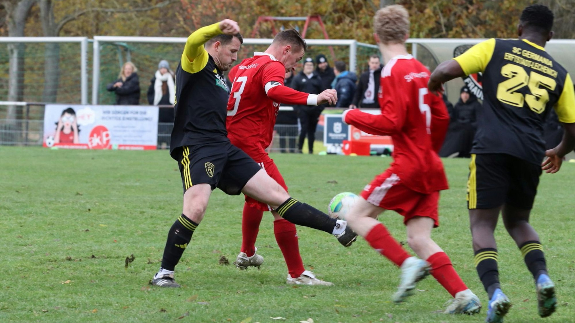 Ein Mittelfeldzweikampf zwischen zwei Spielern, einer stochert von hinten nach dem Ball.