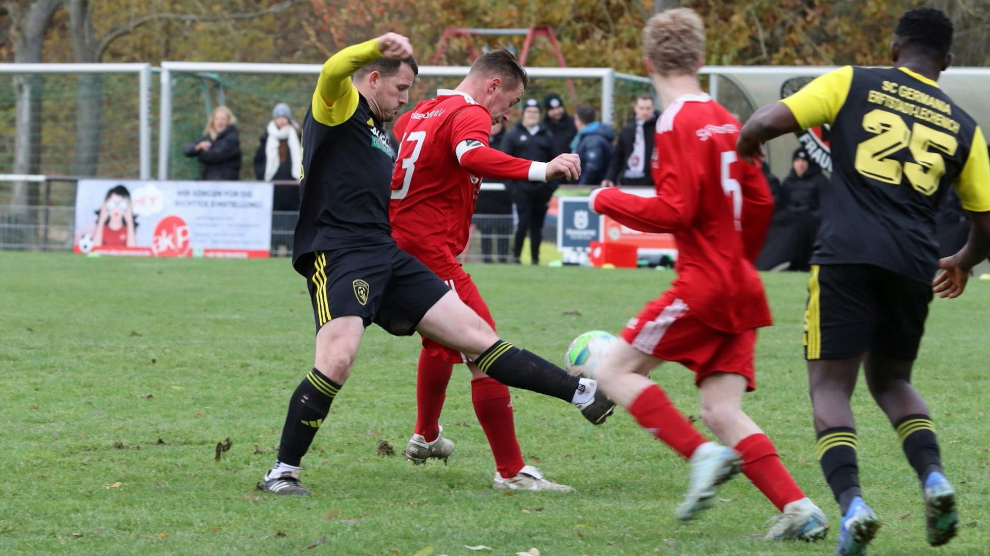 Ein Mittelfeldzweikampf zwischen zwei Spielern, einer stochert von hinten nach dem Ball.