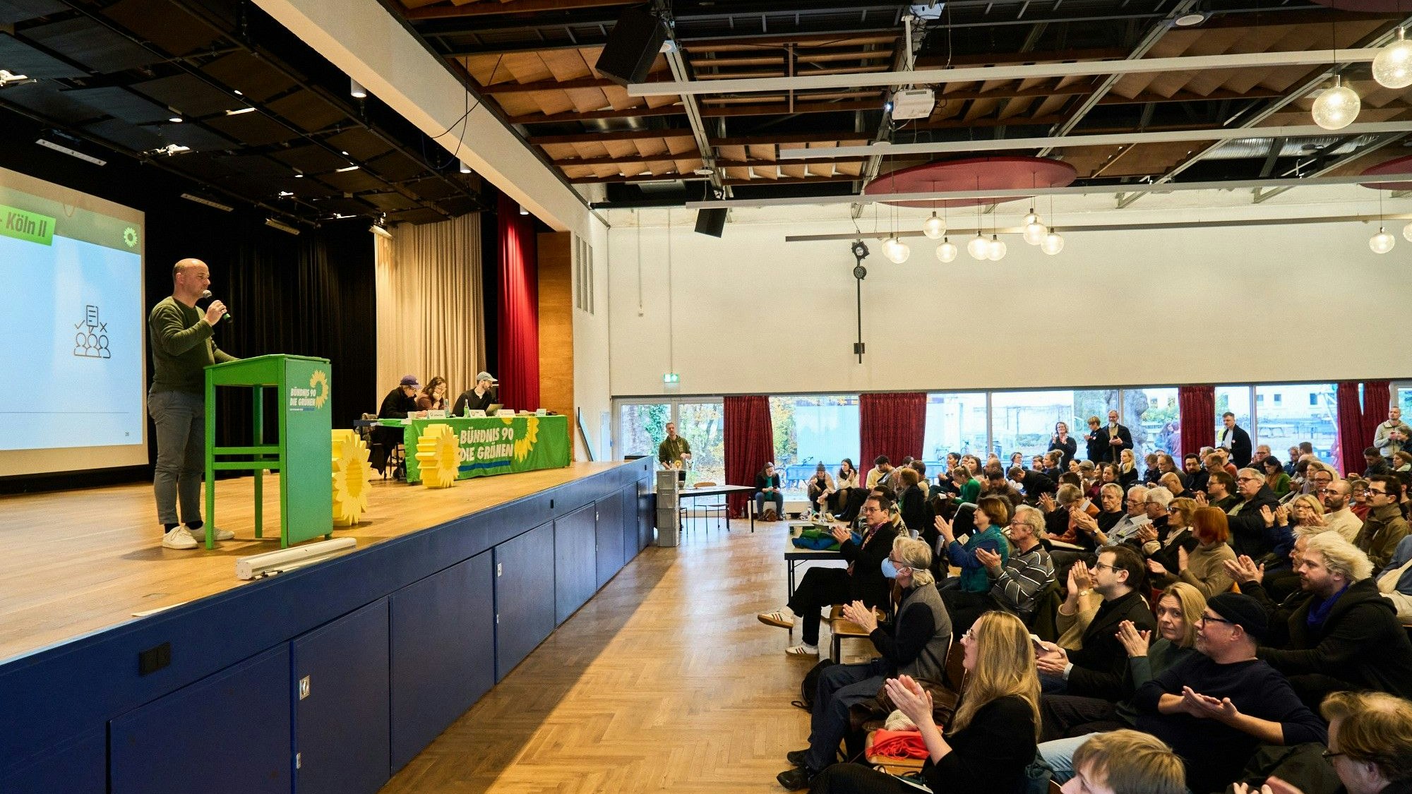 Bei der Mitgliederversammlung der Kölner Grünen steht Staatssekretär Sven Lehmann am Rednerpult.