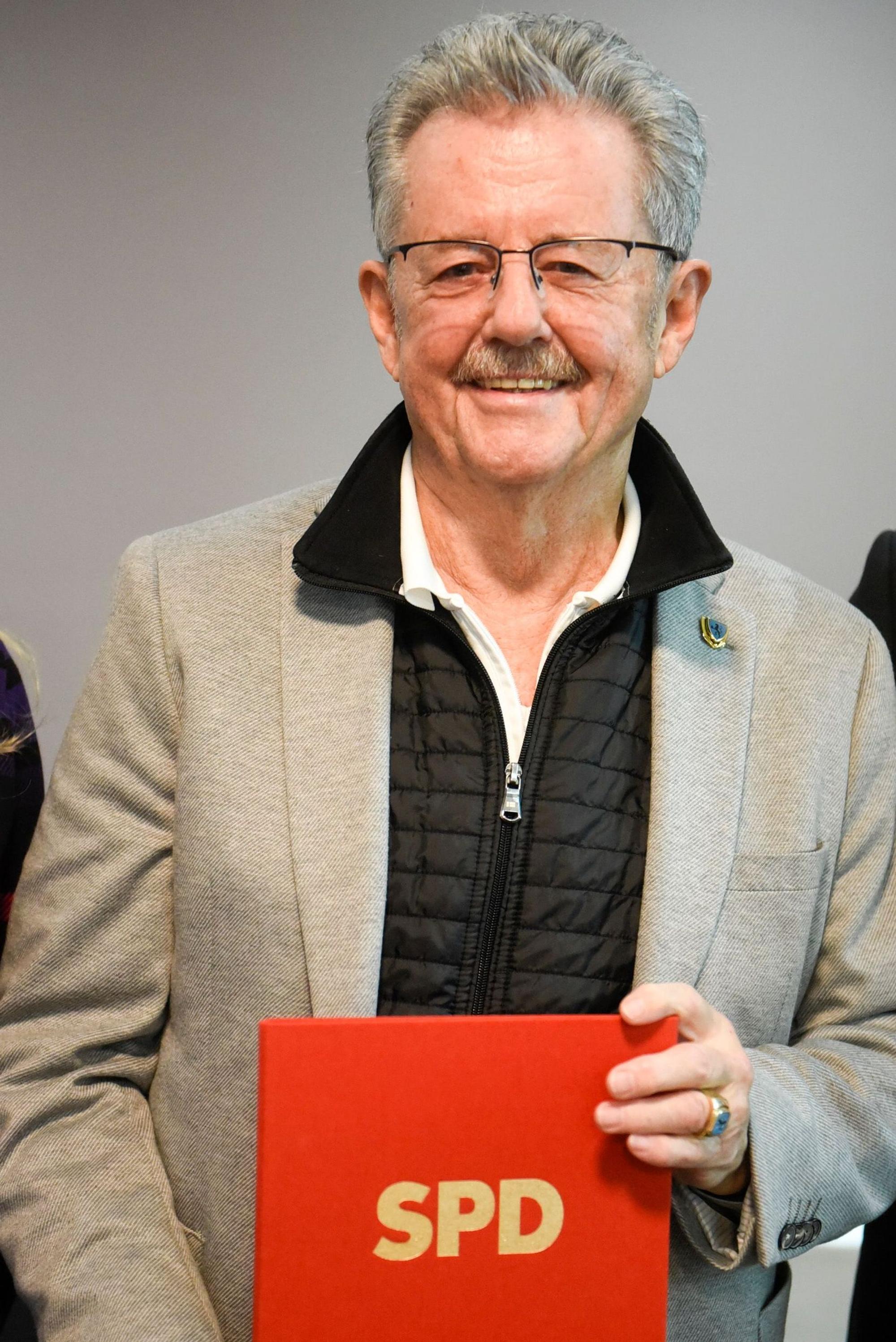 Auf dem Bild ist ein Mann zu sehen, der eine Urkunde für die 50-jährige Mitgliedschaft in der SPD in die Kamera hält.