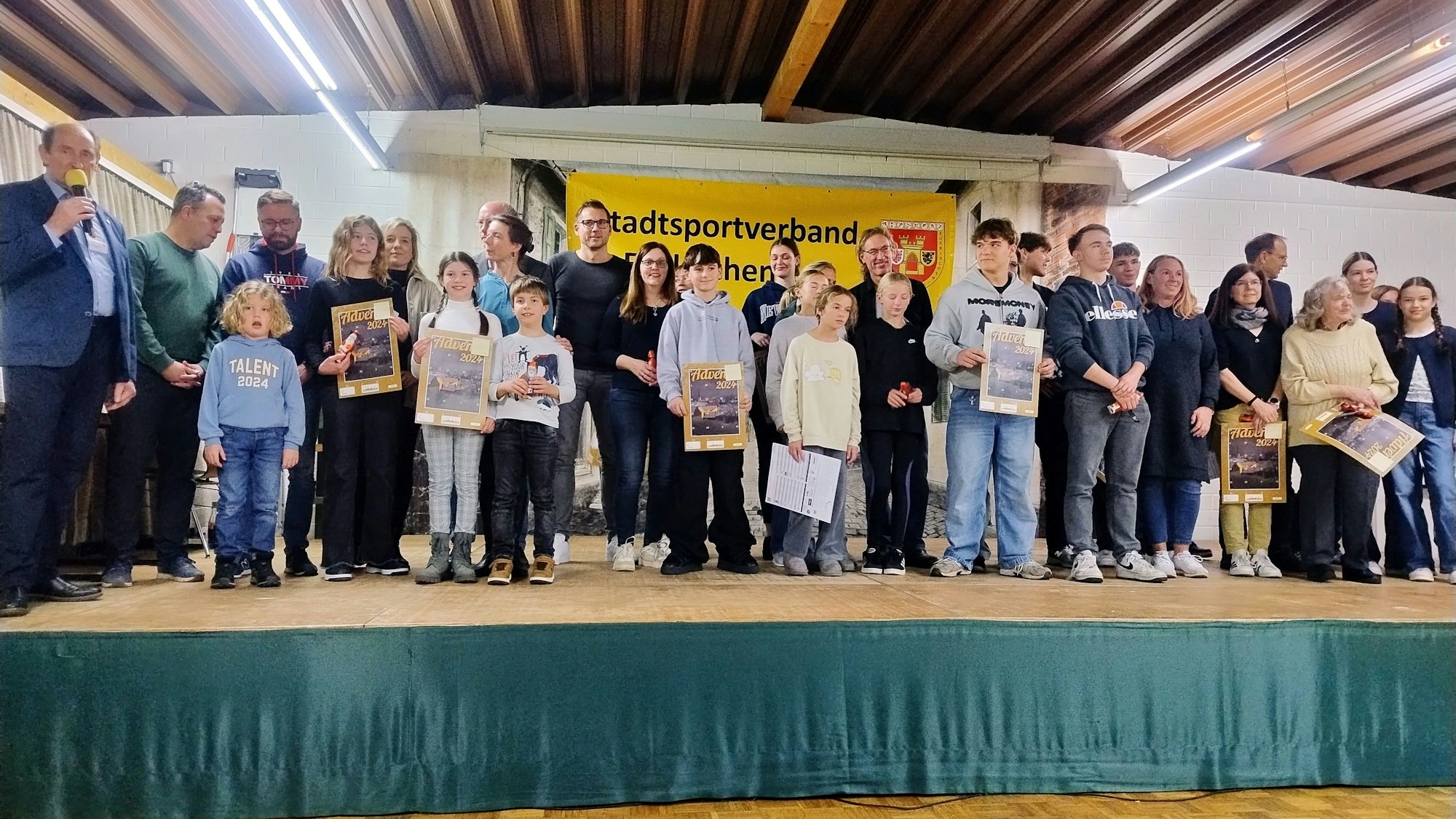 Einige der insgesamt 218 Sportabzeichenabsolventen stehen mit ihren Urkunden auf der Bühne des Schützenhauses in Kuchenheim.