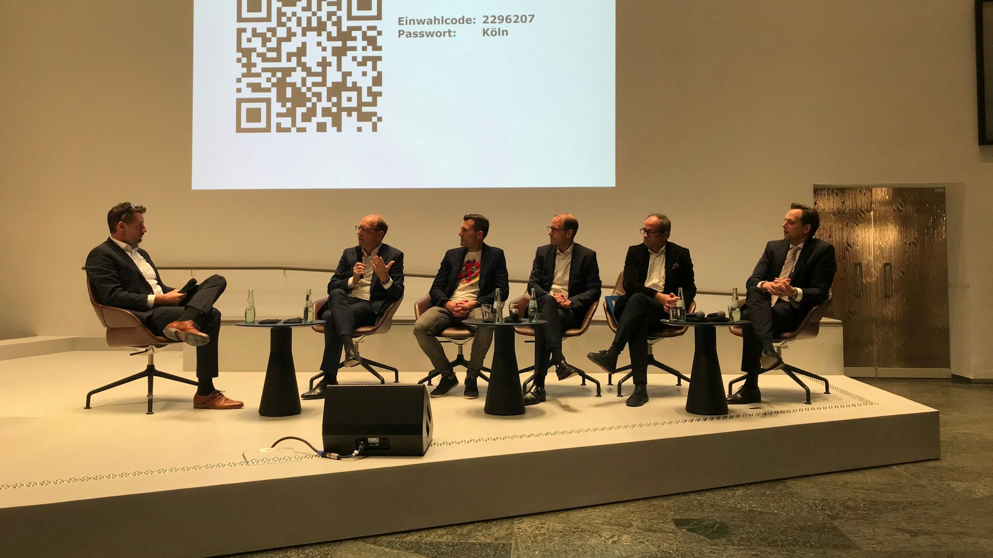 Moderator Sven Butler (v. l.), Timo von Lepel (Netcologne), Klaus Müller (Telekom), Sechs Männer sitzen nebeneinander auf einer Bühne.