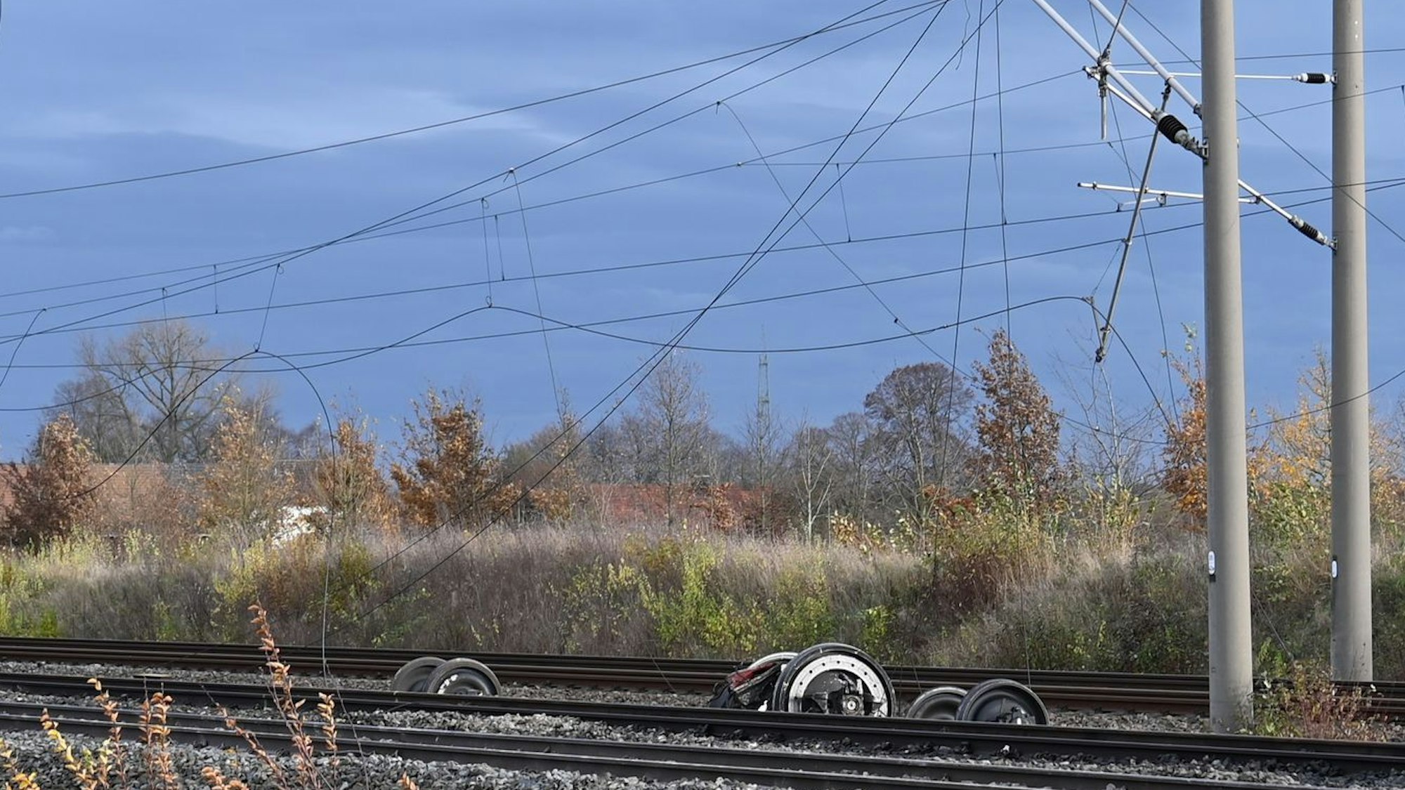 Das Bild zeigt herunterhängende Oberleitungen sowie Achsen und Räder an der Unfallstelle.