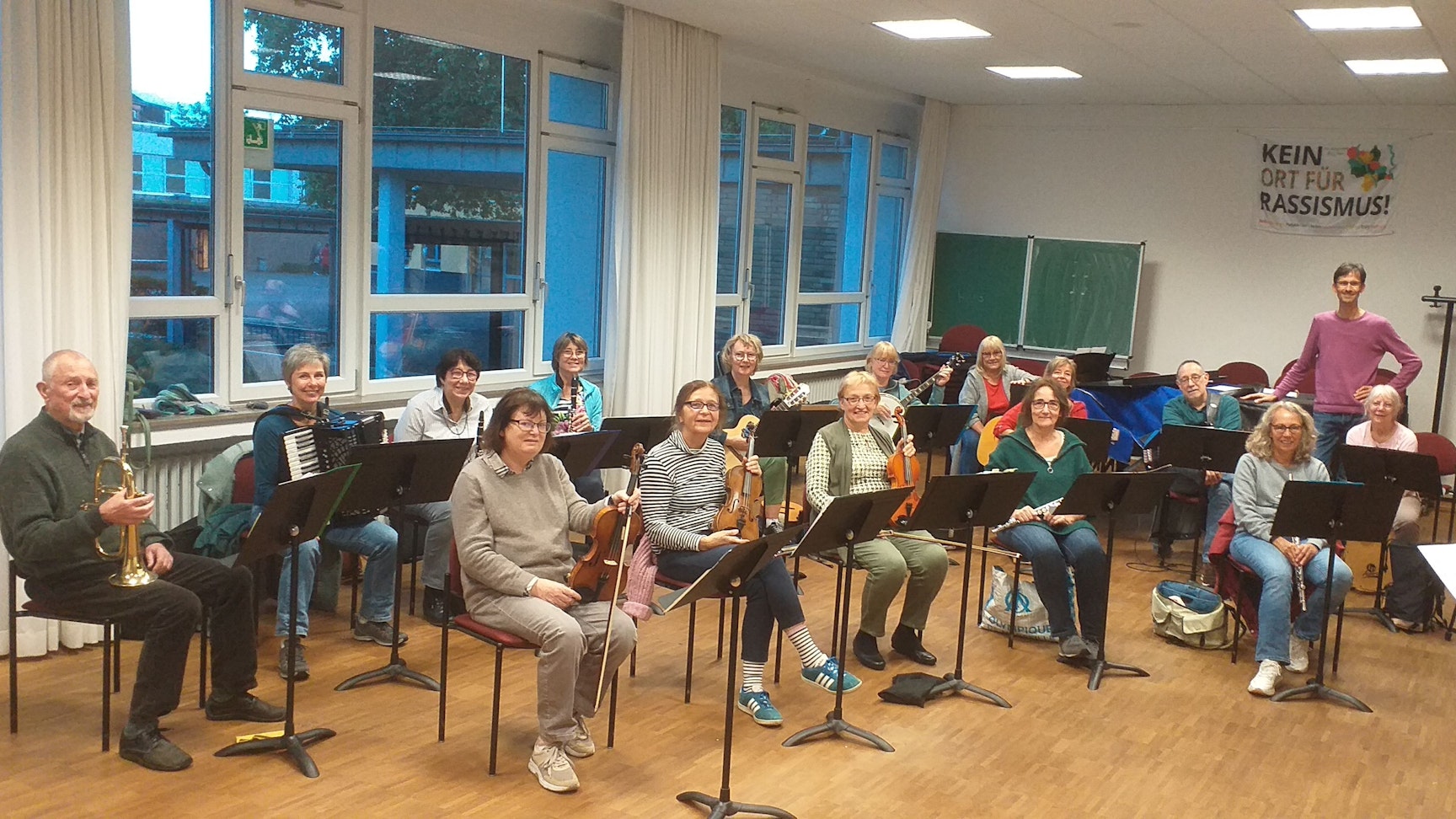 Das Foto zeigt die Mitglieder des Ensembles mit ihren Instrumenten sitzend hinter Notenständern.