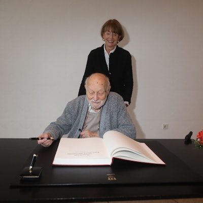 Kurt Marx trägt sich in das Gästebuch der Stadt Köln ein. Henriette Reker steht hinter ihm.