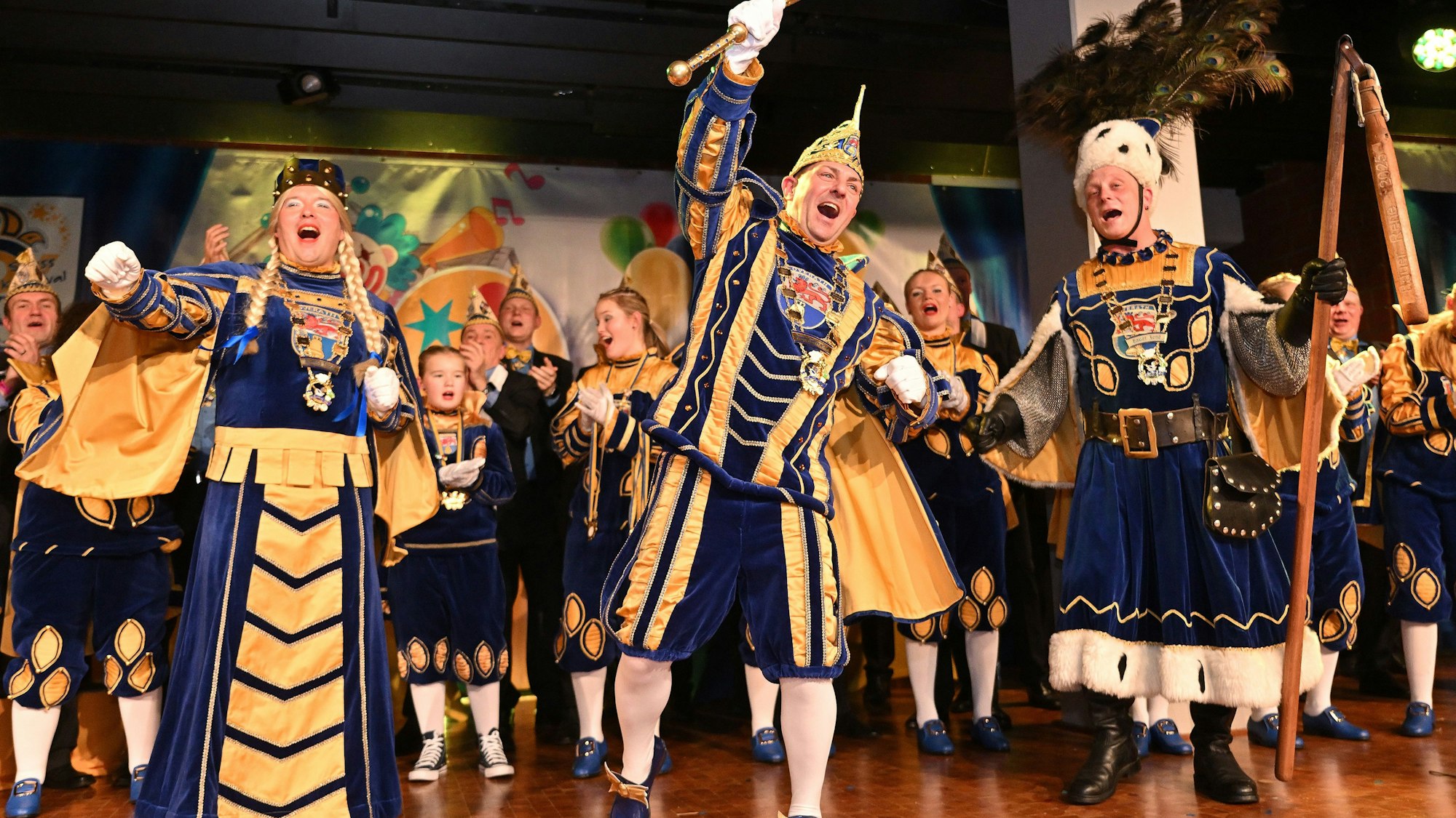 Das Obverather Dreigestirn steht auf der Bühne der Cyriax-Aula bei der Kostümsitzung mit Proklamation.