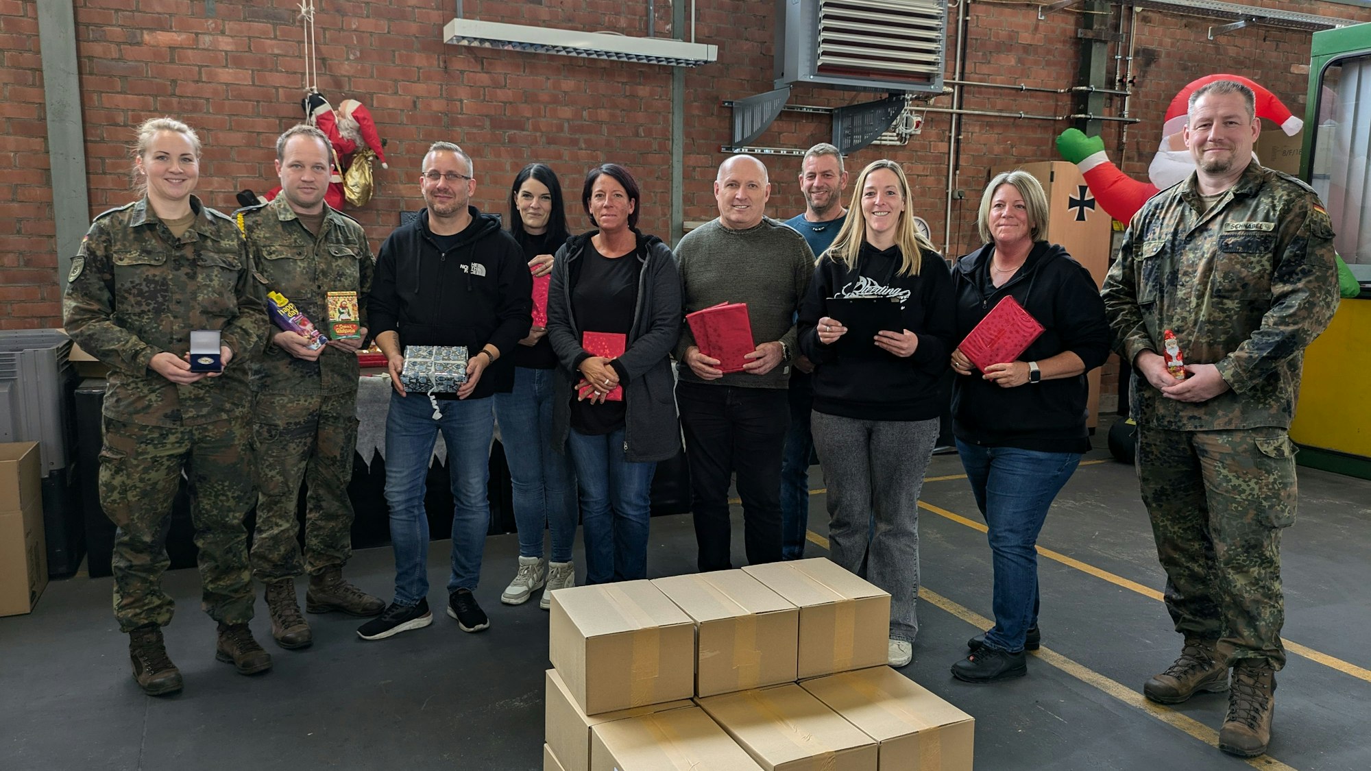 Die Beteiligten haben sich um einige aufgestapelte Pakete aufgestellt.